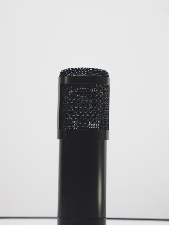Close-up of a black microphone against a white backdrop, perfect for audio recording themes.